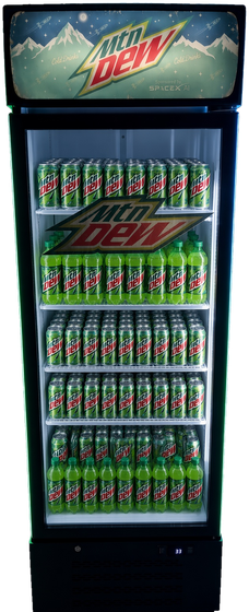 The soda machine: a glass-door cooler stocked with Mtn Dew, lit green from inside, with an illuminated retro Mtn Dew lightbox mounted on top.
